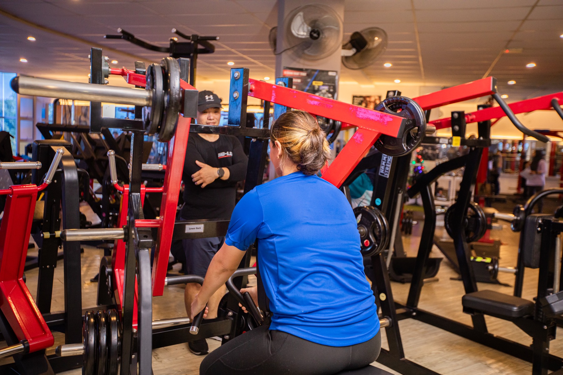 Coach Ho coaching a participant on a plate-loaded strength machine